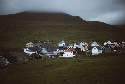 Houses on field by mountains against sky