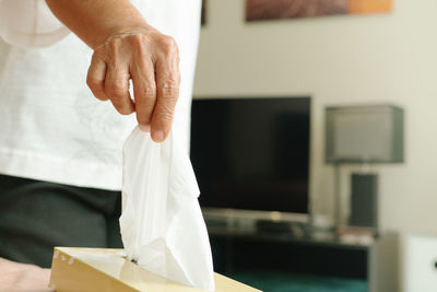 Midsection of woman holding white at home