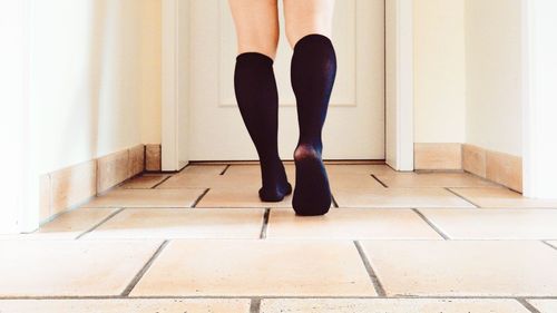 Low section of woman walking on floor at home