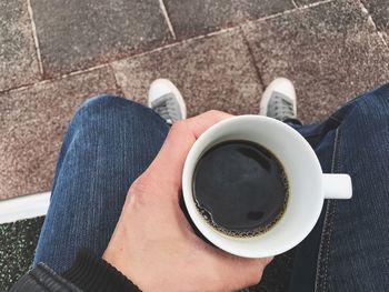 Low section of woman holding coffee cup