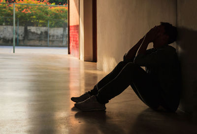 Depressed man silhouette man sitting against wall