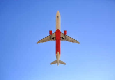 Low angle view of airplane against clear blue sky