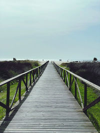 View of wooden footbridge against clear sky