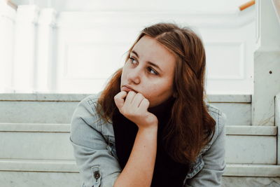 Thoughtful woman with hand on chin sitting on steps