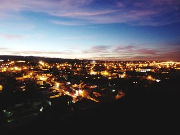 High angle view of illuminated cityscape against blue sky