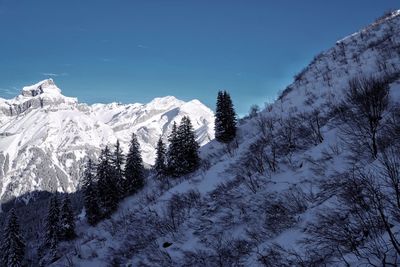 Scenic view of snow covered mountains against blue sky