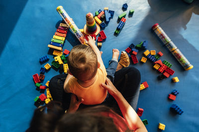 High angle view of mother holding boy playing with toys at home