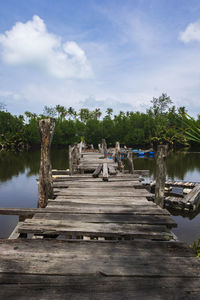 Wooden pier by lake against sky