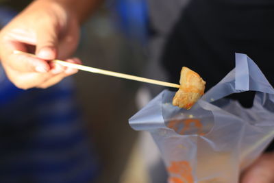 Cropped hand holding skewer with food