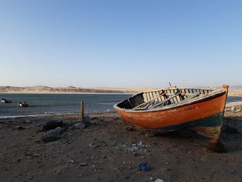 Boat moored on beach against sky