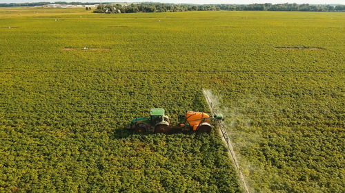 Tractor spraying the chemicals on the large green field. spraying the herbicides on the farm land. 