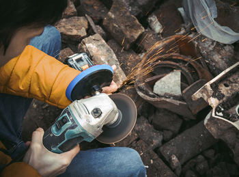 A young caucasian man in a yellow jacket is holding a drill and polishing with a disc