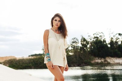 Portrait of young woman standing by lake