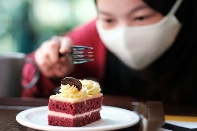 Young woman wearing mask eating pastry