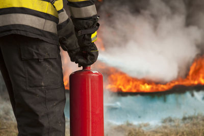 Midsection of firefighter spraying fire hydrant