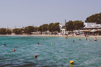 People swimming in pool against clear sky