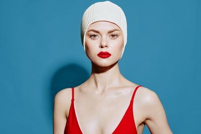 Portrait of young woman against blue background