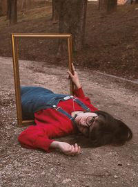Portrait of woman with picture frame lying on field