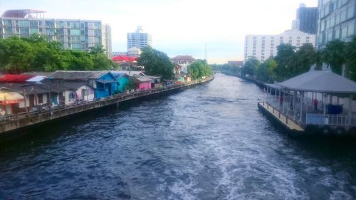 Canal in city against sky