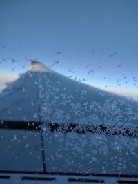 Close-up of ice on window against sky