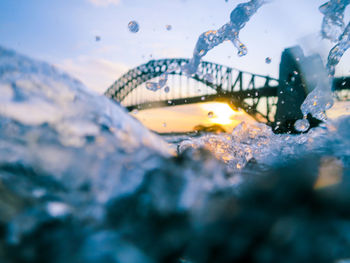 Waves splashing in sea with bridge on background