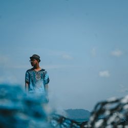 Young man looking at sea against sky