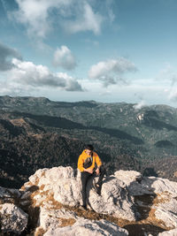 People on rock by mountain against sky