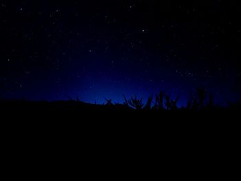 Low angle view of silhouette landscape against star field at night