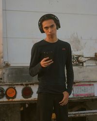 Portrait of young man standing against wall