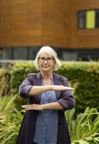 Woman with arms raised standing against plants