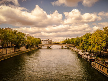 Bridge over river against cloudy sky