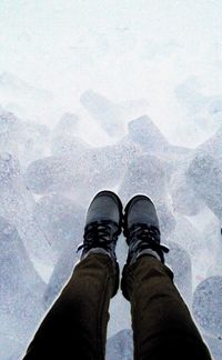 Low section of man standing on snow covered landscape