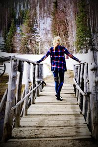 Rear view of man walking on footbridge
