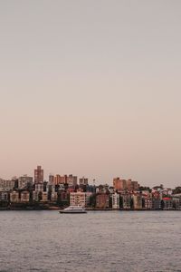 Sea by buildings against clear sky