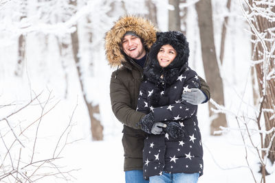 Happy woman standing on snow covered tree