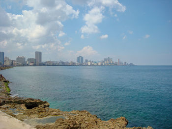 Scenic view of sea by buildings against sky