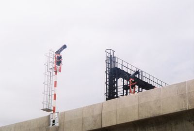 Low angle view of crane at construction site against sky