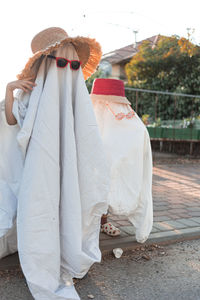 Trendy sheet ghosts costumes on little kids standing on a suburbs street. happy halloween holiday