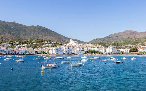 Boats moored in sea against clear blue sky