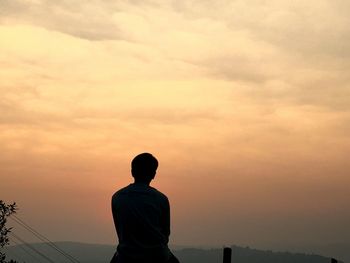 Rear view of man against cloudy sky during sunset