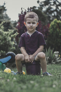 Boy sitting on grass against plants