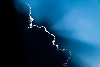 Low angle view of silhouette water against blue sky