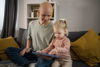 Side view of boy using laptop while sitting on sofa at home