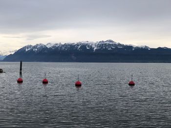 Buoys in lake against sky during winter