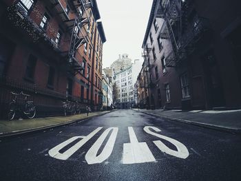 Road sign on street in city against sky