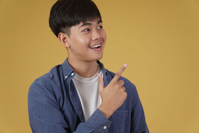 Portrait of smiling boy standing against yellow background