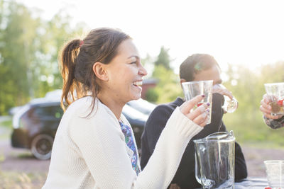 Happy woman having drink with friends at garden party