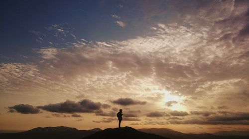 Silhouette of people standing on landscape at sunset