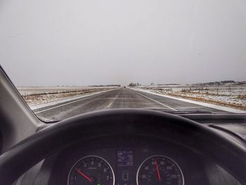 Cars moving on road against sky seen through car windshield