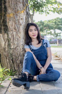 Young woman sitting on tree trunk